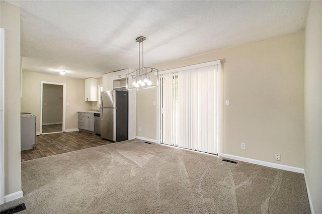 kitchen featuring hanging light fixtures, stainless steel appliances, white cabinets, a chandelier, and dark colored carpet