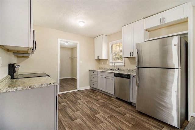 kitchen with white cabinets, appliances with stainless steel finishes, dark hardwood / wood-style floors, and sink