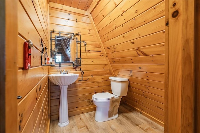 bathroom with wooden ceiling, toilet, wood finished floors, and wood walls