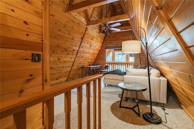 living area with lofted ceiling with beams, an upstairs landing, wooden walls, and wood ceiling