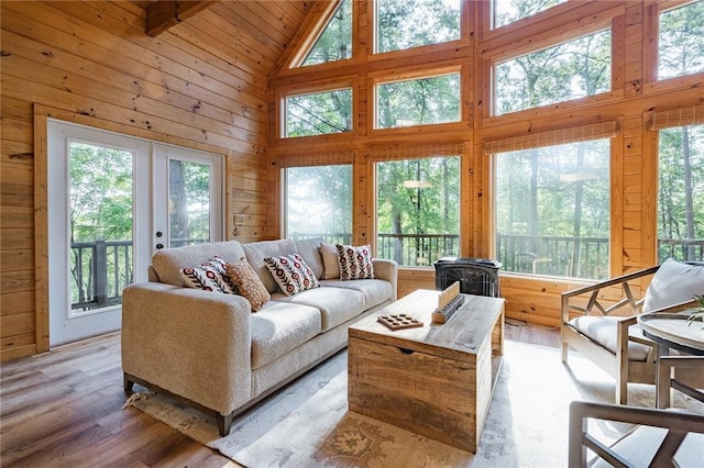 living room featuring wood finished floors, plenty of natural light, wood walls, and a wood stove