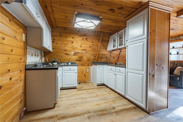 kitchen with dark countertops, wood walls, wooden ceiling, and a sink