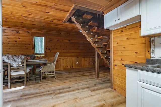 dining area featuring light wood-style floors, wood ceiling, and wood walls