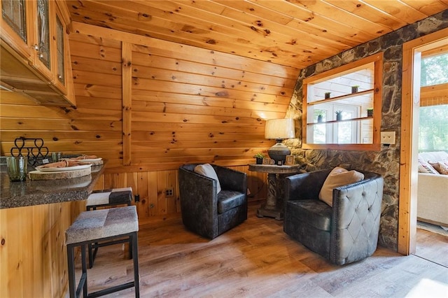 sitting room with light wood-style floors, wooden ceiling, and wood walls