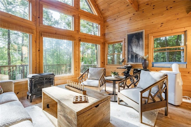 sunroom featuring a wealth of natural light, wooden ceiling, a wood stove, and vaulted ceiling