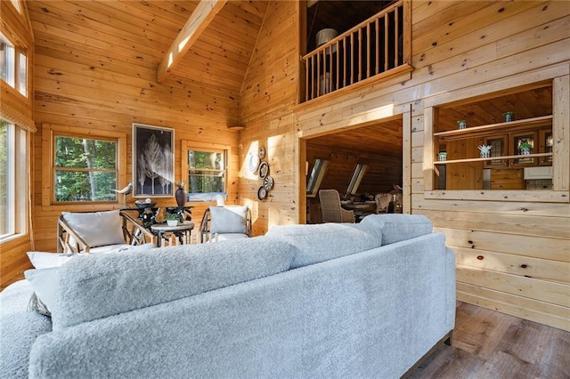 living room with wooden walls, wood ceiling, beam ceiling, wood finished floors, and high vaulted ceiling