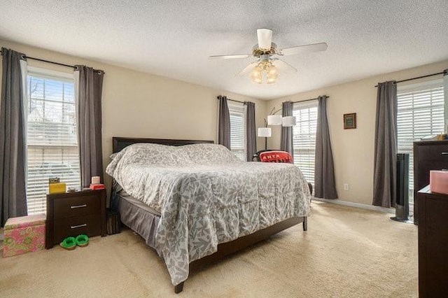 bedroom featuring ceiling fan, light colored carpet, and a textured ceiling