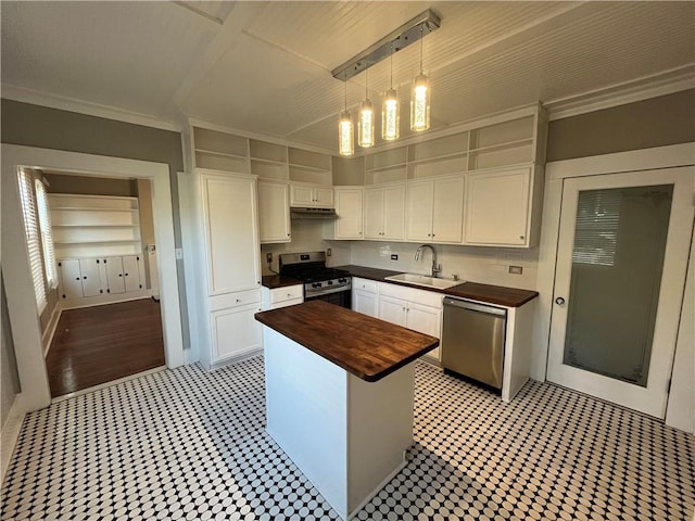 kitchen featuring stainless steel appliances, butcher block countertops, a sink, and white cabinets