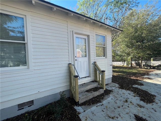 entrance to property featuring crawl space and fence