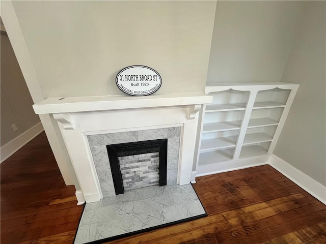 interior details featuring a fireplace, wood finished floors, and baseboards