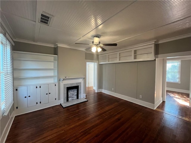 unfurnished living room with crown molding, visible vents, a fireplace with raised hearth, dark wood-type flooring, and a ceiling fan