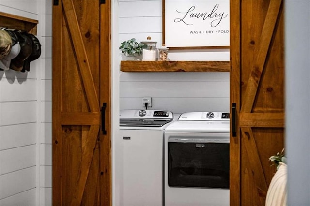 clothes washing area featuring washer and dryer and a barn door