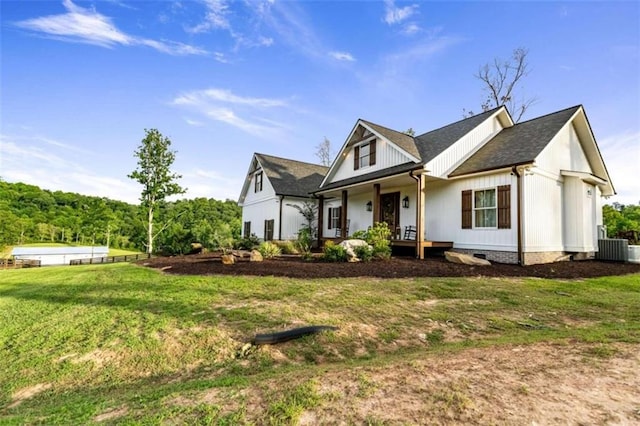 view of front of home with a porch, a front lawn, and central AC