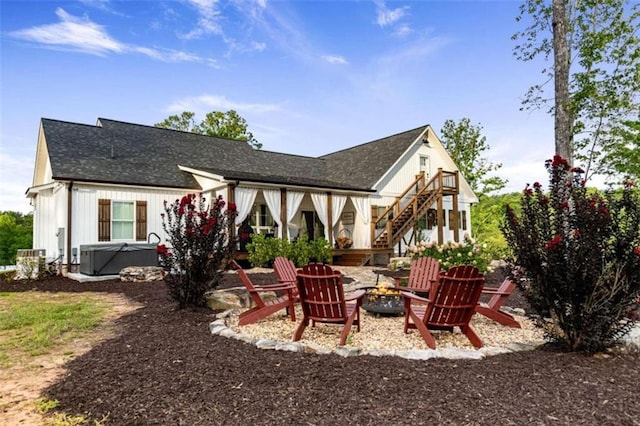 back of property featuring a patio, a hot tub, an outdoor fire pit, and central AC