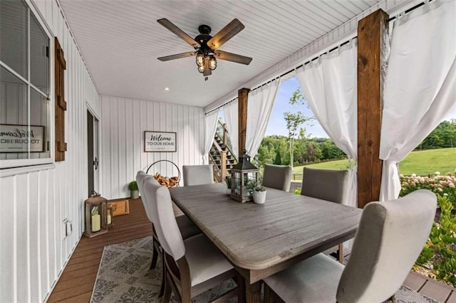 dining area featuring ceiling fan, wooden walls, and hardwood / wood-style floors