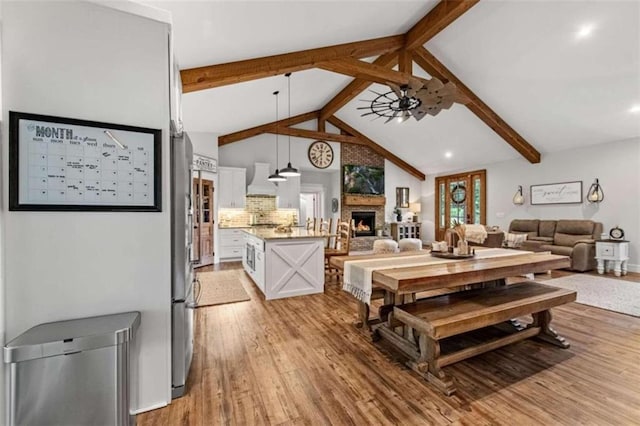 dining area featuring light hardwood / wood-style floors, high vaulted ceiling, beam ceiling, and ceiling fan