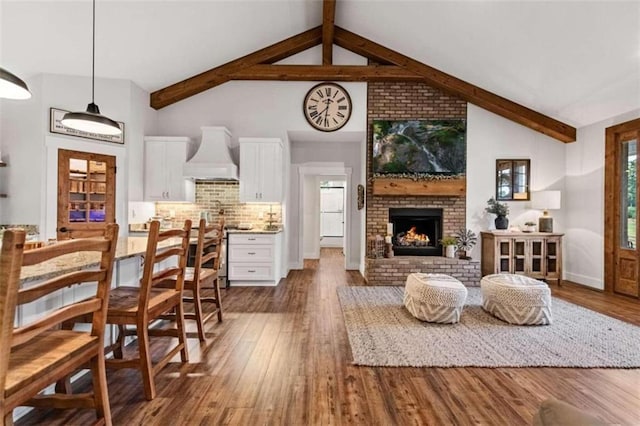 living room featuring beamed ceiling, dark wood-type flooring, a brick fireplace, and high vaulted ceiling