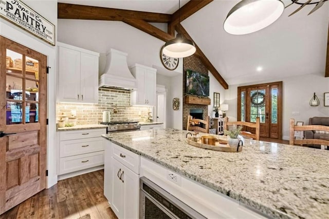 kitchen with premium range hood, vaulted ceiling with beams, wood-type flooring, and white cabinets