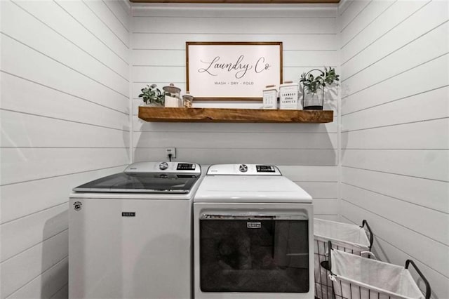 washroom featuring wooden walls and separate washer and dryer