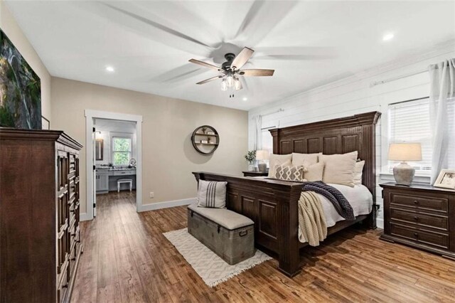 bedroom with dark hardwood / wood-style floors, ensuite bathroom, and ceiling fan