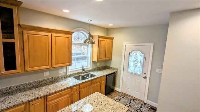 kitchen with a wealth of natural light, sink, light stone countertops, and black dishwasher