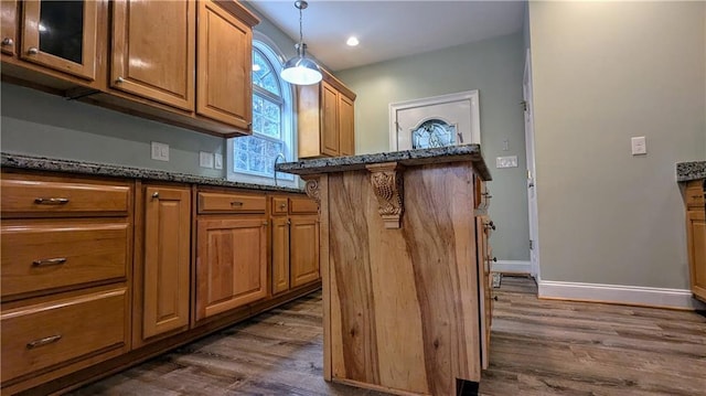 kitchen featuring dark stone countertops, dark wood-type flooring, and pendant lighting