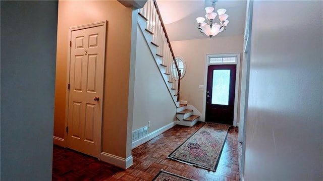 foyer entrance with dark parquet flooring and a chandelier