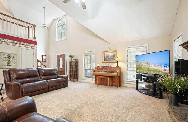 carpeted living room with ceiling fan and high vaulted ceiling