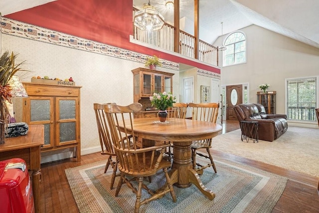 dining room featuring high vaulted ceiling, a notable chandelier, and dark hardwood / wood-style flooring