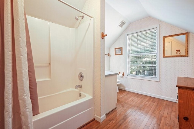 full bathroom with wood-type flooring, vaulted ceiling, toilet, shower / bath combo with shower curtain, and vanity