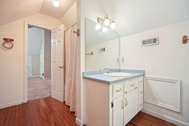 bathroom with vanity, wood-type flooring, and vaulted ceiling