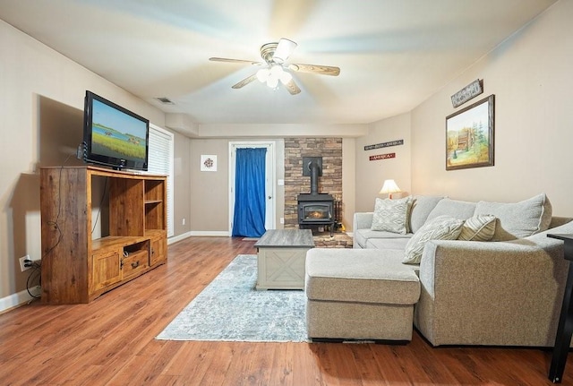 living room with hardwood / wood-style flooring, a wood stove, and ceiling fan