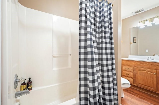 full bathroom featuring toilet, shower / tub combo with curtain, hardwood / wood-style flooring, and vanity