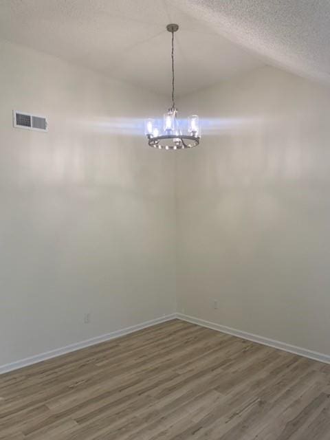 unfurnished dining area with dark hardwood / wood-style flooring, vaulted ceiling, a chandelier, and a textured ceiling