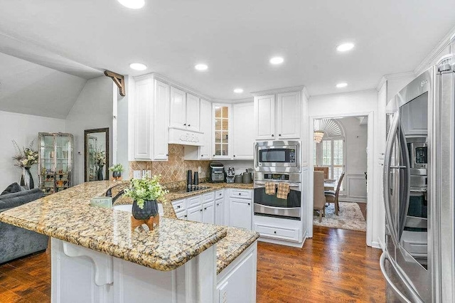 kitchen featuring dark wood-type flooring, kitchen peninsula, light stone countertops, white cabinets, and appliances with stainless steel finishes