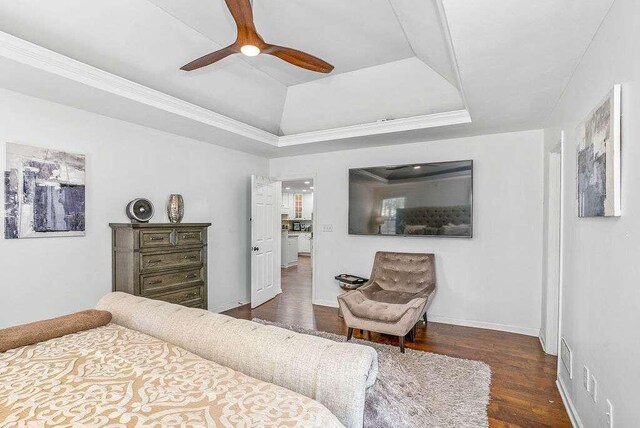 bedroom with crown molding, dark hardwood / wood-style floors, a raised ceiling, and ceiling fan