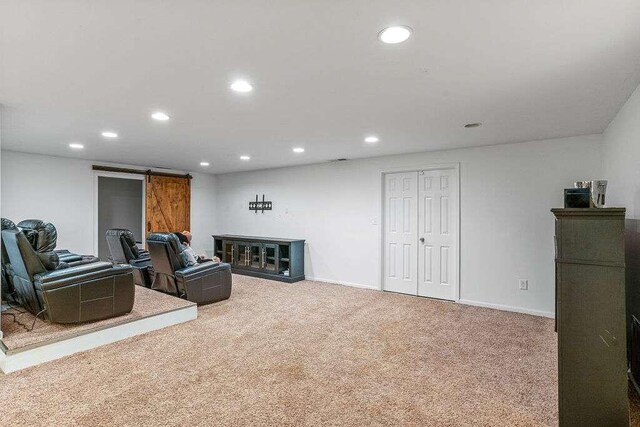 sitting room with a barn door and carpet flooring