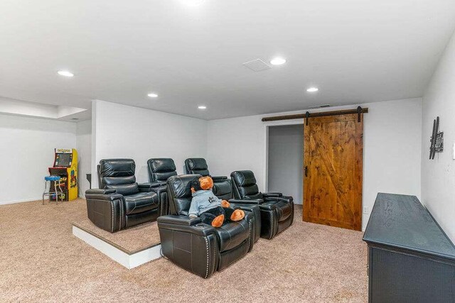 carpeted home theater featuring a barn door