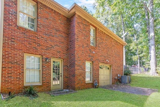 rear view of house featuring a garage, cooling unit, and a lawn