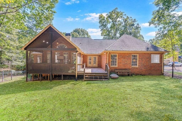 rear view of property featuring a sunroom and a lawn