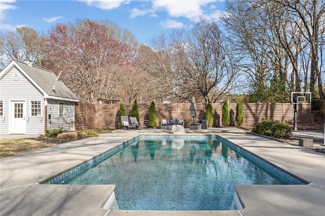 view of swimming pool with a fenced backyard, an outbuilding, and a patio area