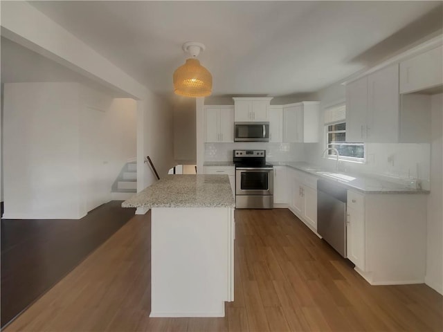 2217 Troutdale Dr, Decatur, GA 30032 - kitchen with white cabinets, dark wood-style floors, a kitchen island, appliances with stainless steel finishes, and light stone countertops