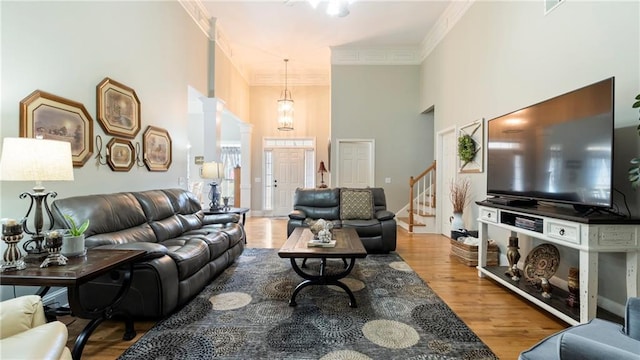 living room featuring hardwood / wood-style floors, a towering ceiling, and ornamental molding