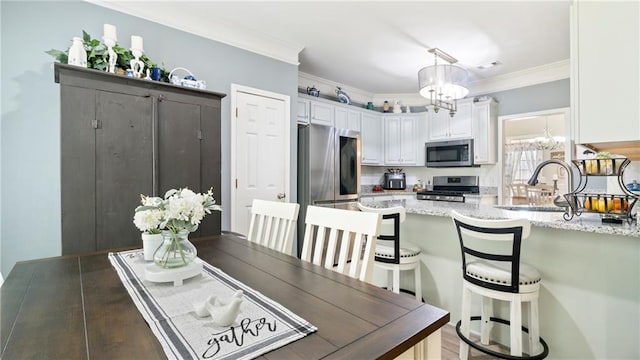 dining area with wood-type flooring, a notable chandelier, ornamental molding, and sink