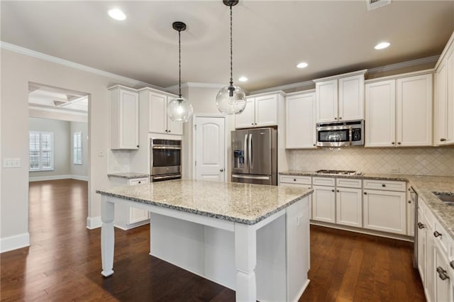 kitchen with stainless steel appliances, a center island, light stone counters, white cabinets, and decorative light fixtures