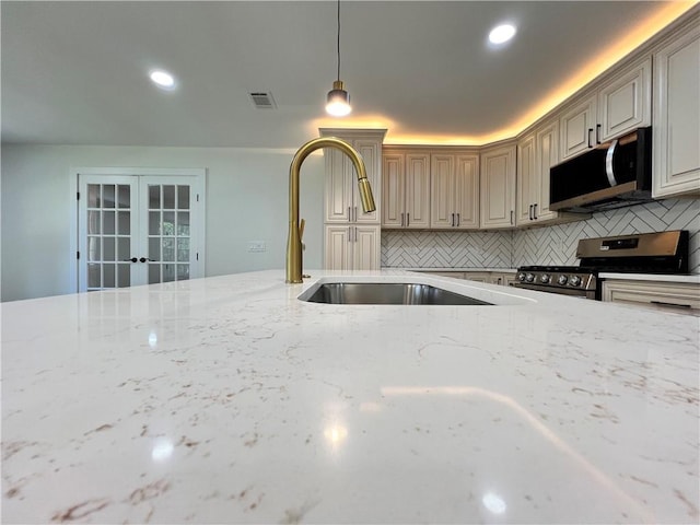 kitchen featuring light stone counters, a sink, french doors, stainless steel appliances, and visible vents