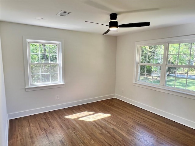 unfurnished room with baseboards, visible vents, and dark wood-style floors