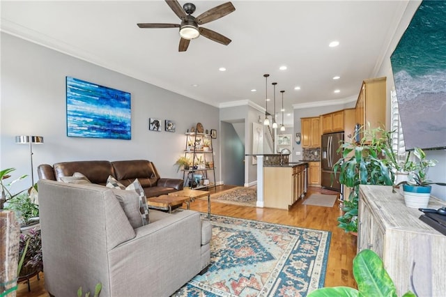 living room with sink, ceiling fan, ornamental molding, and light hardwood / wood-style flooring