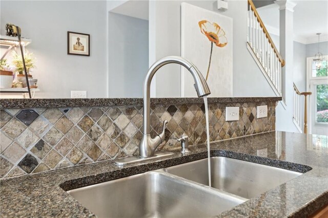 details featuring sink, dark stone countertops, backsplash, and decorative columns