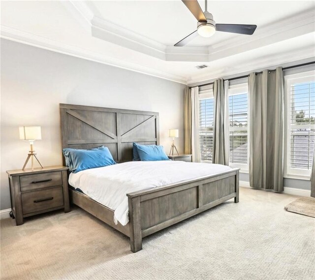 bedroom with ceiling fan, crown molding, light carpet, and a raised ceiling